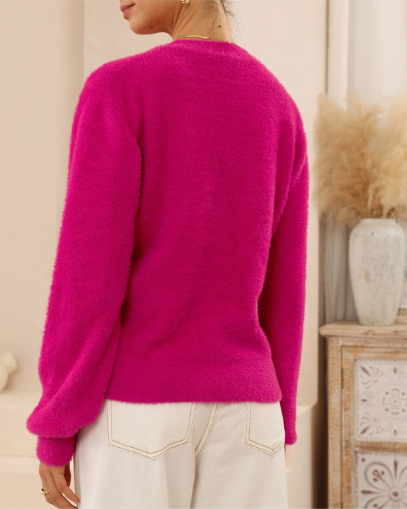 Person wearing a bright pink sweater in a neutral setting
